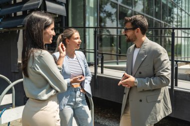 Takım çalışması becerileri. Bir grup genç iş adamı ofis binası dışında fikirler üzerinde çalışıyor. İş adamı ve iş kadını iş yerinde yeni fırsatları tartışıyor ve hazırlıyorlar..