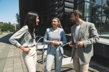 Takım çalışması becerileri. Bir grup genç iş adamı ofis binası dışında fikirler üzerinde çalışıyor. İş adamı ve iş kadını iş yerinde yeni fırsatları tartışıyor ve hazırlıyorlar..