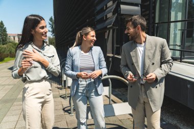 Takım çalışması becerileri. Bir grup genç iş adamı ofis binası dışında fikirler üzerinde çalışıyor. İş adamı ve iş kadını iş yerinde yeni fırsatları tartışıyor ve hazırlıyorlar..
