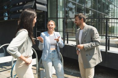Takım çalışması becerileri. Bir grup genç iş adamı ofis binası dışında fikirler üzerinde çalışıyor. İş adamı ve iş kadını iş yerinde yeni fırsatları tartışıyor ve hazırlıyorlar..