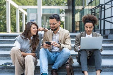 Ofis binasının dışında çalışan ve konuşan üç farklı iş adamı. Erkek ve kadın. Planları ve iş projelerini tartışıyorlar. İş adamı ve iş kadını takım çalışması.