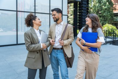 Ofis binasının dışında çalışan ve konuşan üç farklı iş adamı. Erkek ve kadın. Planları ve iş projelerini tartışıyorlar. İş adamı ve iş kadını takım çalışması.