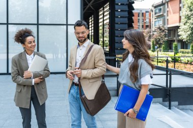 Ofis binasının dışında çalışan ve konuşan üç farklı iş adamı. Erkek ve kadın. Planları ve iş projelerini tartışıyorlar. İş adamı ve iş kadını takım çalışması.