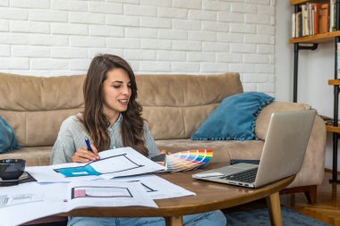 Yan koşuşturma. Genç mimarlık ve şehircilik üniversite öğrencisi kadın serbest meslek evde müşteriyle çalışan iç mimar olarak iletişim ve video çağrısı için dizüstü bilgisayar kullanıyor.