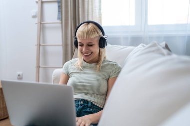 Genç, mutlu, serbest çalışan bir işçi ya da üniversiteli bir kadın evinde oturmuş dizüstü bilgisayarla çalışıyor, podcast dinliyor ya da en sevdiği şarkıyı dinliyor, özgürlüğün ve bağımsızlığın tadını çıkarıyor..