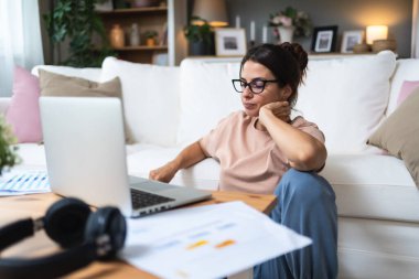 Genç, yorgun ve çok çalışan, evde çalışan, işten yorgun ve yorgun bir kadın. Profesyonel finans ve ekonomi uzmanı video çağrısından sonra yorgun düştü.