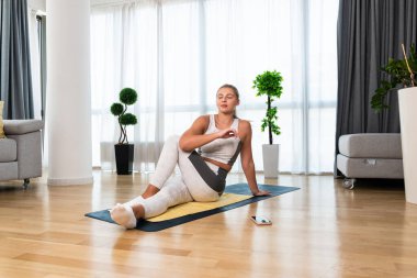 Ev antrenmanı. Genç, mutlu, kendine güveni tam bir kadın evinde spor antrenmanı yapıyor, kaslarını esnetiyor ve daha iyi bir yaşam ve başarı için egzersiz yapıyor..
