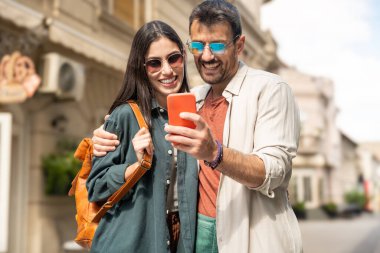 Güzel, genç, alternatif hippi turistler şehir caddesinde yürüyen, kucaklaşan, modern, havalı kıyafetler giyen çiftler. Modaya uygun ve şık insanlar. Erkek ve kadın hayattan zevk alıyor.