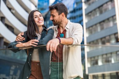 Genç ve mutlu bir çift emlakçılarının yeni dairelerini gezdirmesini bekliyor. Erkek ve kadın yeni evlerinin apartmanının önünde bekliyorlar..