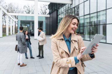 Bir grup iş adamı ofis binasının önünde. İş kadını ve iş adamı konuşuyor ve tartışıyorlar, iş dışında, fikir alışverişinde bulunuyorlar, selamlaşıyorlar, iş sisteminin yenilikleri hakkında konuşuyorlar..
