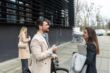 Bir grup iş adamı ofis binasının önünde. İş kadını ve iş adamı konuşuyor ve tartışıyorlar, iş dışında, fikir alışverişinde bulunuyorlar, selamlaşıyorlar, iş sisteminin yenilikleri hakkında konuşuyorlar..
