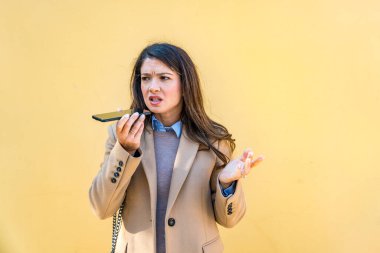 Şehir sokaklarında tartışan genç bir iş kadını iş arkadaşına ya da sevgilisine sesli mesaj göndermek için akıllı telefon kullanıyor. Profesyonel meslek kadını telefonda bağırıyor.