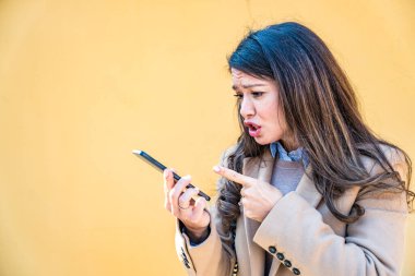 Şehir sokaklarında tartışan genç bir iş kadını iş arkadaşına ya da sevgilisine sesli mesaj göndermek için akıllı telefon kullanıyor. Profesyonel meslek kadını telefonda bağırıyor.