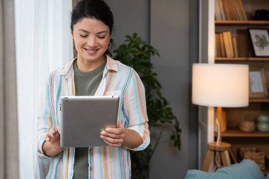 Ev ofisinde dijital tablet üzerinde çalışan çekici bir kadın. İş kadını küçük bir şirket sahibi dairesinden internet üzerinden çalışıyor. Bağımsız serbest grafik tasarımcı kadın özgürlük ve işin tadını çıkarıyor.