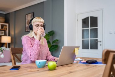 Finans ve ekonomi. Genç bir kadın, küçük bir işletme sahibi, ev ofisinde çalışıyor, sunum ve çevrimiçi koçluk için video çağrısına hazırlanıyor. E-ticaret, profesyonel mesleki serbest meslek