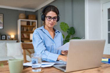 Finans ve ekonomi. Genç bir kadın, küçük bir işletme sahibi, ev ofisinde çalışıyor, sunum ve çevrimiçi koçluk için video çağrısına hazırlanıyor. E-ticaret, profesyonel mesleki serbest meslek