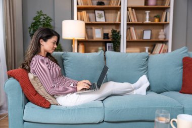 Konsantre olmuş milenyum dişisi, evinde dizüstü bilgisayarla internette gezinirken tembelce bir hafta sonu boyunca bilgisayar sörfü yaparak internetten internet alışverişi yapmakla meşgul.