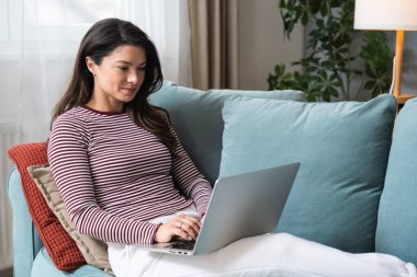 Konsantre olmuş milenyum dişisi, evinde dizüstü bilgisayarla internette gezinirken tembelce bir hafta sonu boyunca bilgisayar sörfü yaparak internetten internet alışverişi yapmakla meşgul.