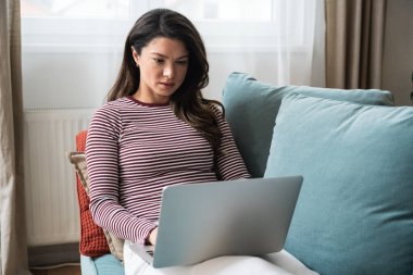 Konsantre olmuş milenyum dişisi, evinde dizüstü bilgisayarla internette gezinirken tembelce bir hafta sonu boyunca bilgisayar sörfü yaparak internetten internet alışverişi yapmakla meşgul.