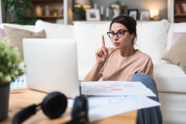 Genç serbest çalışan bir iş kadını, apartman dairesinde çalışıyor müşterisi, finans ve ekonomi uzmanı ile video görüşmesi yapıyor, dizüstü bilgisayarlı webcam üzerinden danışmanlık yapıyor. Mesleki meslek