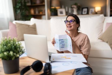 Genç serbest çalışan bir iş kadını, apartman dairesinde çalışıyor müşterisi, finans ve ekonomi uzmanı ile video görüşmesi yapıyor, dizüstü bilgisayarlı webcam üzerinden danışmanlık yapıyor. Mesleki meslek