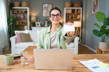 Serbest çalışan genç bir iş kadını, evde çalışıyor, işe ara veriyor, kredi kartını online alışveriş ve alım için kullanıyor. Happy, internete para harcıyorsun..