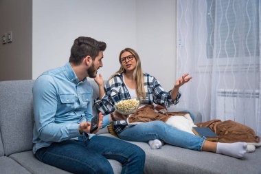 Akşam evde oturan genç çift televizyon programı ve ne izleyecekleri hakkında tartışıyorlar. Erkekler spor ya da aksiyon ister, kadınlar aşk filmi ya da TV şovu ister..