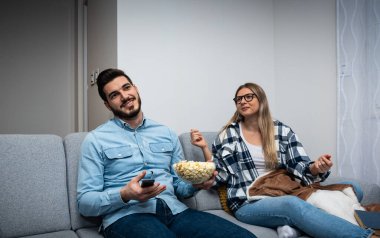 Akşam evde oturan genç çift televizyon programı ve ne izleyecekleri hakkında tartışıyorlar. Erkekler spor ya da aksiyon ister, kadınlar aşk filmi ya da TV şovu ister..