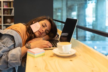 Serbest çalışan genç bir iş kadını, çalışmaktan yorgun ve yorgun, kütüphanede dizüstü bilgisayarla tembel tembel çalışıyor. Stresli ve endişeli kadın yeni projede beyin fırtınası yapıyor. Yenilikçi fikirler.