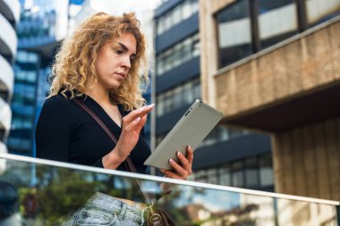 Genç, zeki ve başarılı bir stajyer patron ve müşterilerle görüşmeden önce ofis binasının önünde dijital tabletle dikiliyor. İş kadını kendini detaylarla bilgilendirir..