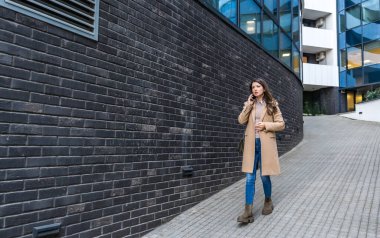 Başarılı bir iş kadını, şirket işinde ofis çalışanı, ofis binasının dışında konuşmak ve iletişim kurmak için akıllı telefonu kullanıyor. Kendini işine adamış bağımsız güçlü CEO kadın çalışma süresinin sonu.