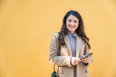 Başarılı bir iş kadınının portresi, resmi kıyafetler içinde sarı ya da turuncu duvarın önünde duran bir ofis çalışanı. Güçlü bağımsız profesyonel işgal kadın lider pozu.