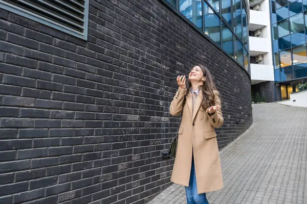 Başarılı bir iş kadını, şirket işinde ofis çalışanı, ofis binasının dışında konuşmak ve iletişim kurmak için akıllı telefonu kullanıyor. Kendini işine adamış bağımsız güçlü CEO kadın çalışma süresinin sonu.