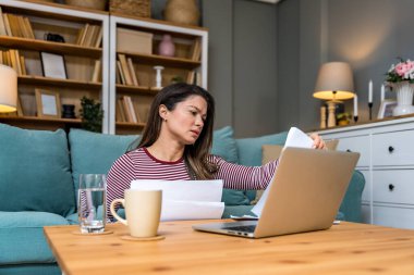 Finansal kriz. Genç endişeli iş kadını evde oturmuş, istatistik ve dizüstü bilgisayar kullanarak küçük küresel işletme şirketinin gelir ve giderlerini hesaplamaya çalışıyor..