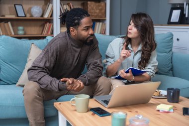 Genç, zeki, yenilikçi bir çift yeni iş fikirlerini dizüstü bilgisayarla sunuyorlar. Evde kanepede oturup potansiyel yatırımcılarla konuşuyorlar. Teknoloji yeniliği.