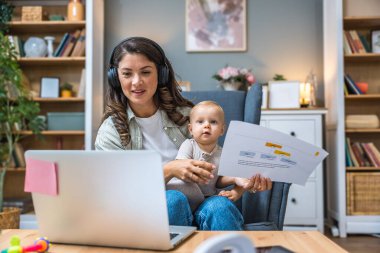 Genç, zeki, yenilikçi bekar anne dizüstü bilgisayarla yeni iş fikrini sunuyor, evde bebekle oturuyor, potansiyel yatırımcıyla konuşuyor. Teknoloji yeniliği.