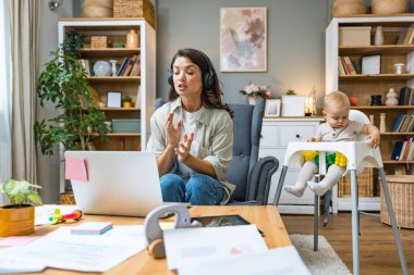 Genç, zeki, yenilikçi bekar anne dizüstü bilgisayarla yeni iş fikrini sunuyor, evde bebekle oturuyor, potansiyel yatırımcıyla konuşuyor. Teknoloji yeniliği.