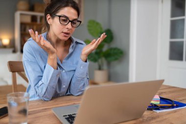 Genç serbest çalışan bir iş kadını dizüstü bilgisayarında video konferansına katılıyor ve evde çalışıyor, projesinde potansiyel yatırımcıyla web kamerasında konuşuyor. Maliye ve ekonomi kavramı.