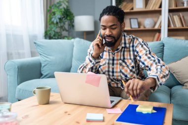 Genç serbest çalışan bir iş adamı dizüstü bilgisayarında video konferansı düzenlerken evde oturuyor ve projesinde potansiyel yatırımcıyla web kamerasında konuşuyor. Maliye ve ekonomi kavramı.