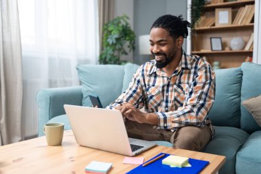 Genç serbest çalışan bir iş adamı dizüstü bilgisayarında video konferansı düzenlerken evde oturuyor ve projesinde potansiyel yatırımcıyla web kamerasında konuşuyor. Maliye ve ekonomi kavramı.