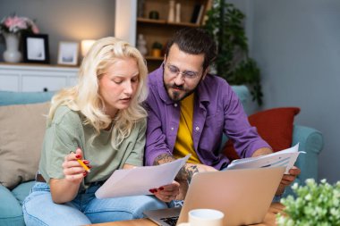 Genç, yenilikçi yenilikçi bir hippi çift yeni iş fikirlerini dizüstü bilgisayarla sunuyorlar, evde çalışıyorlar, potansiyel yatırımcılarla konuşuyorlar. Modern teknoloji yeniliği.