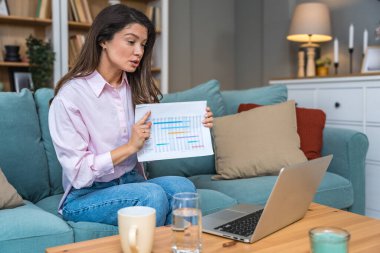 Genç serbest çalışan bir iş kadını dizüstü bilgisayarında video konferansına katılıyor ve evde çalışıyor, projesinde potansiyel yatırımcıyla web kamerasında konuşuyor. Maliye ve ekonomi kavramı.