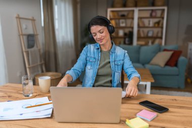 Genç serbest çalışan bir iş kadını dizüstü bilgisayarında video konferansına katılıyor ve evde çalışıyor, projesinde potansiyel yatırımcıyla web kamerasında konuşuyor. Maliye ve ekonomi kavramı.