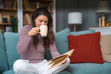 Yaşam dengesi, özgüven, akıl sağlığı ve bağımsızlık. Genç bir kadın küçük modern evinde oturuyor, kahve içiyor ve kitap okuyor. Zihinsel dengesini koruyor ve kendini eğitiyor..