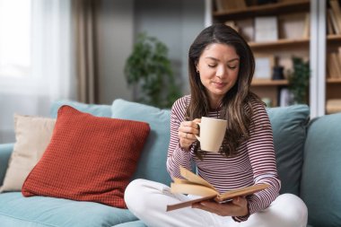 Yaşam dengesi, özgüven, akıl sağlığı ve bağımsızlık. Genç bir kadın küçük modern evinde oturuyor, kahve içiyor ve kitap okuyor. Zihinsel dengesini koruyor ve kendini eğitiyor..