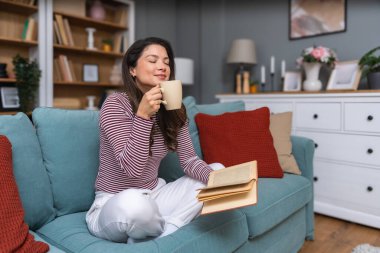 Yaşam dengesi, özgüven, akıl sağlığı ve bağımsızlık. Genç bir kadın küçük modern evinde oturuyor, kahve içiyor ve kitap okuyor. Zihinsel dengesini koruyor ve kendini eğitiyor..