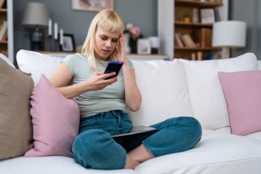 Genç bir kadın rahat koltukta tek başına rahat bir şekilde rahat bir şekilde rahat rahat rahat oturup mesajlaşmak, yayın yapmak, alışveriş yapmak, video sohbeti yapmak, okumak, göz atmak, oyun oynamak, uzaktan çalışmak, bankacılık, öğrenmek, programlamak için akıllı telefon kullanıyor..