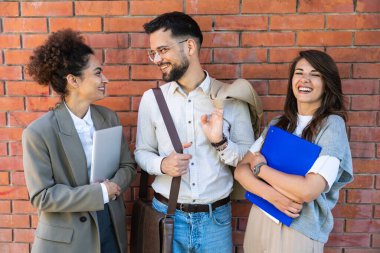 Kurumsal profesyonellerden oluşan çeşitli bir ekip dışarıda iş birliği yapıyor, modern cam ofis binası önünde dizüstü bilgisayardaki verileri analiz ederken stratejik tartışmalara girişiyorlar..