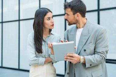 Kurumsal profesyonellerden oluşan çeşitli bir ekip dışarıda iş birliği yapıyor, modern cam ofis binası önünde dizüstü bilgisayardaki verileri analiz ederken stratejik tartışmalara girişiyorlar..