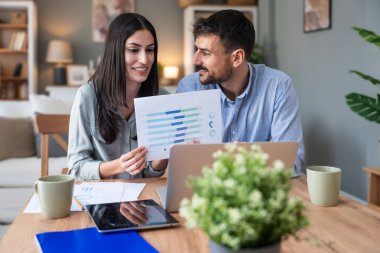 Genç, yenilikçi yenilikçi bir hippi çift yeni iş fikirlerini dizüstü bilgisayarla sunuyorlar, evde çalışıyorlar, potansiyel yatırımcılarla konuşuyorlar. Modern teknoloji yeniliği.